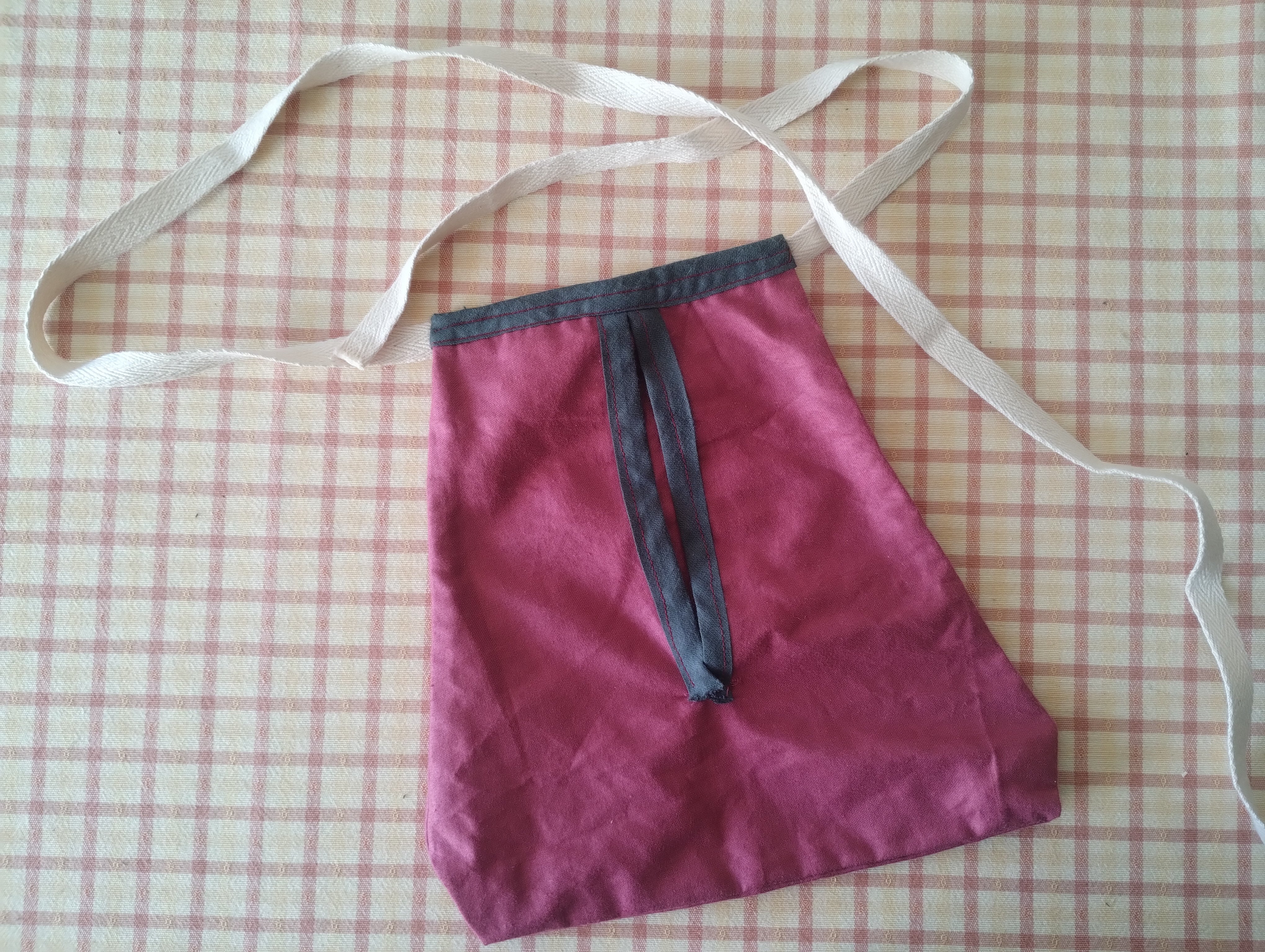 A hand-sewn burgundy tie-on pocket with a long cotton tape tie