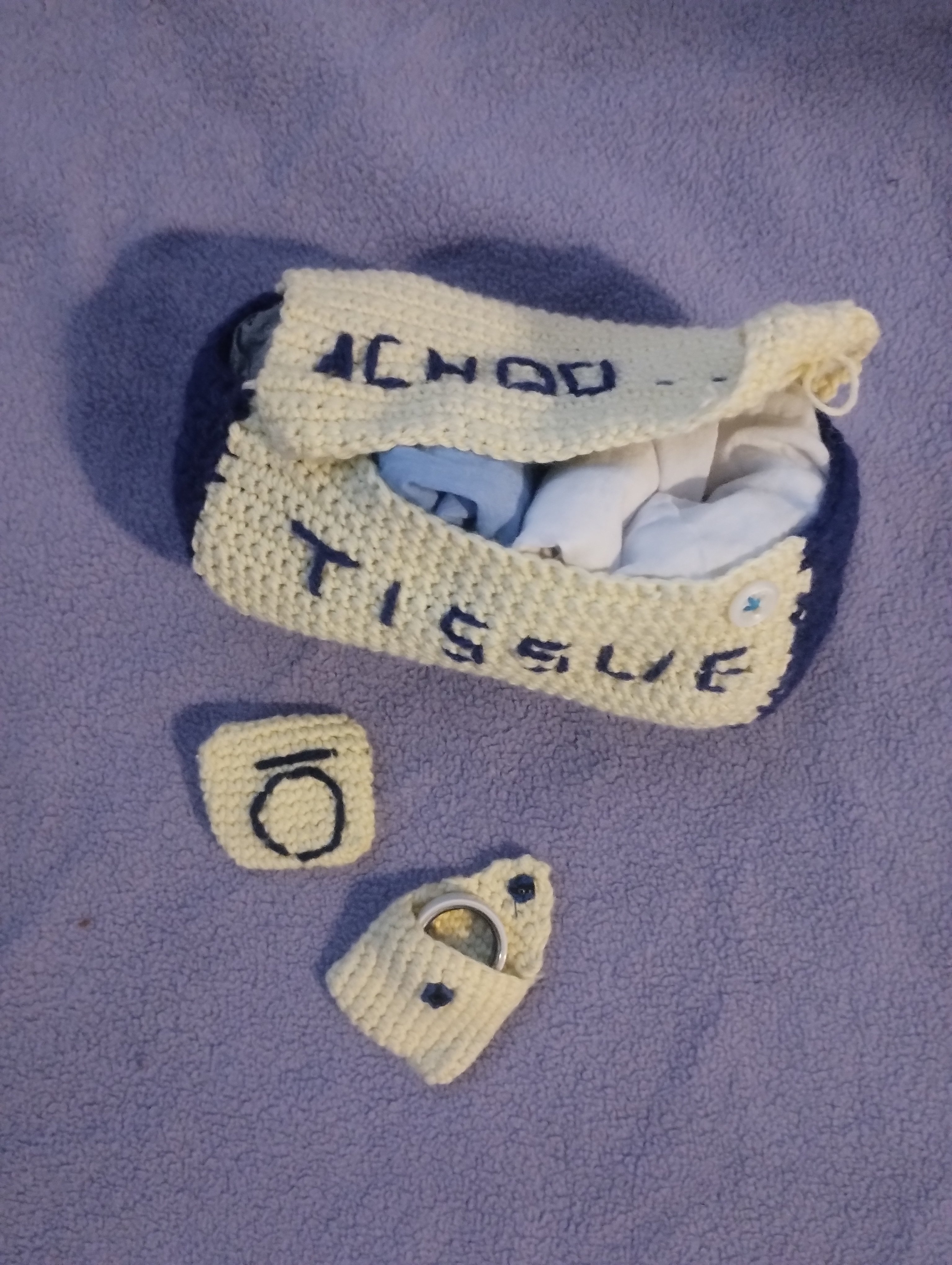 A crocheted pencil case next to two small matching pouches, a round coin purse and a patch embroidered with a circle and the number 10