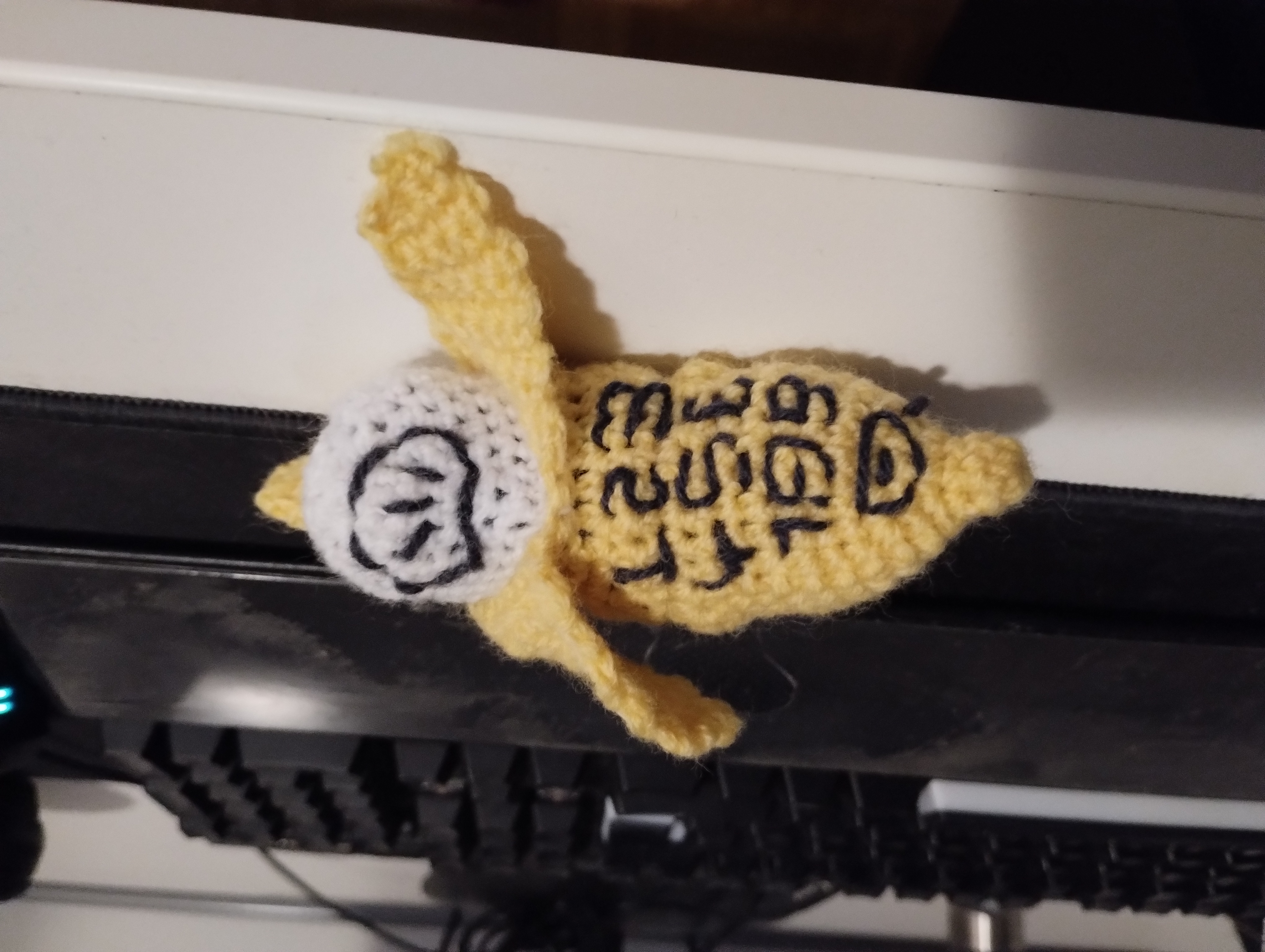 A crocheted banana-shaped phone case embroidered with "banana phone"