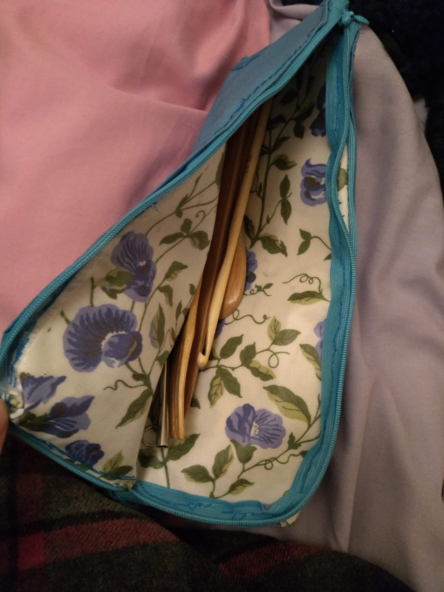 A zipped, floral-lined cutlery pouch holding a set of reusable wooden utensils