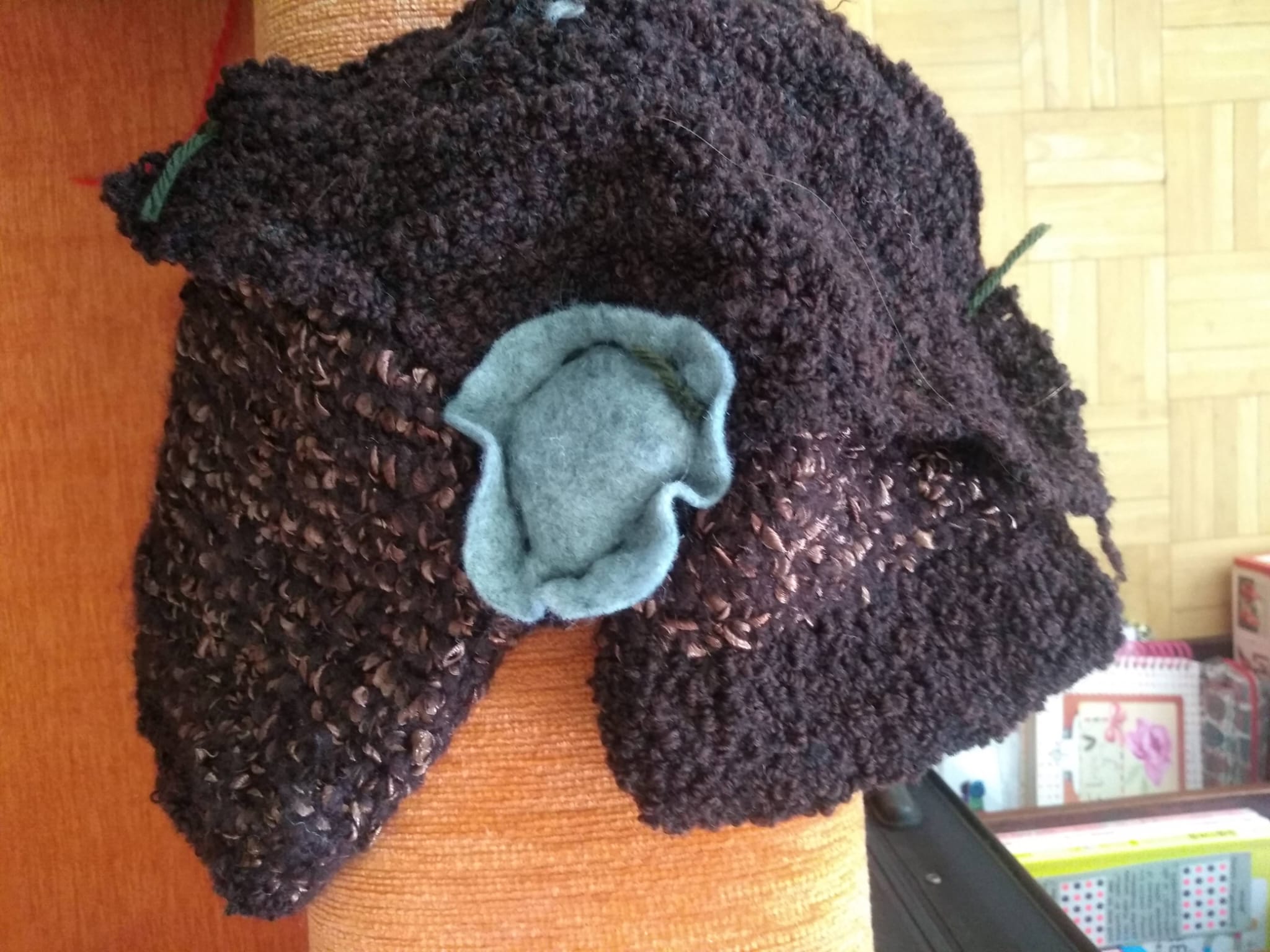 A textured brown knitted pouch with a soft grey-blue lining tucked inside