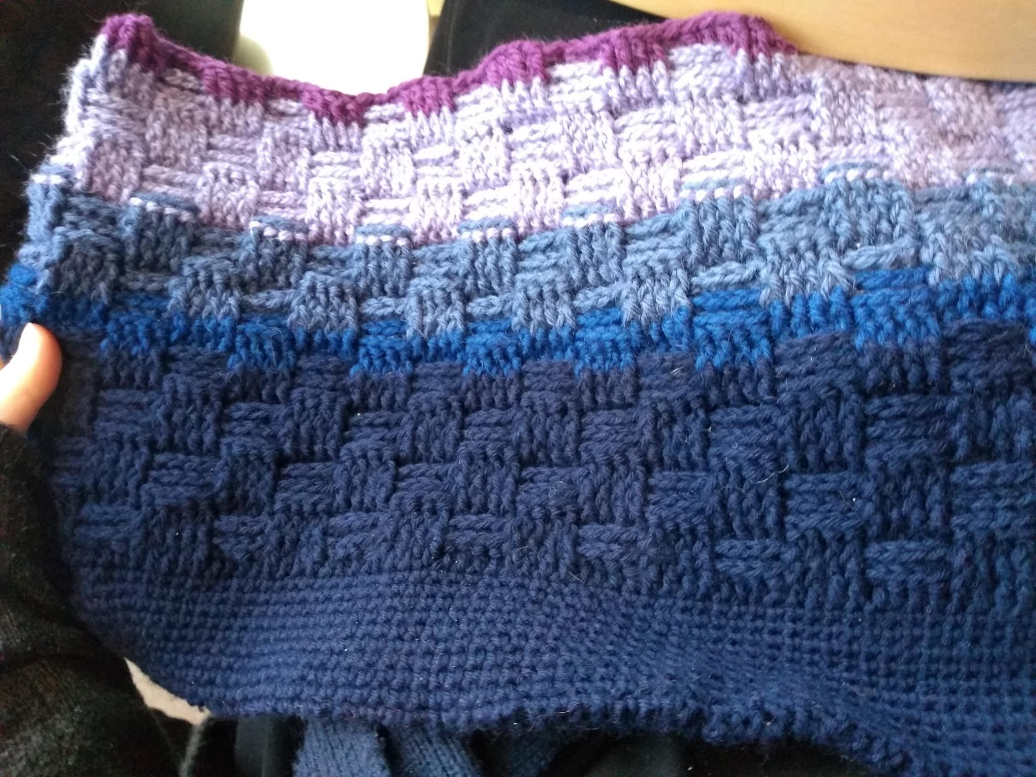 A crocheted basketweave laptop sleeve shading from navy through blue to magenta