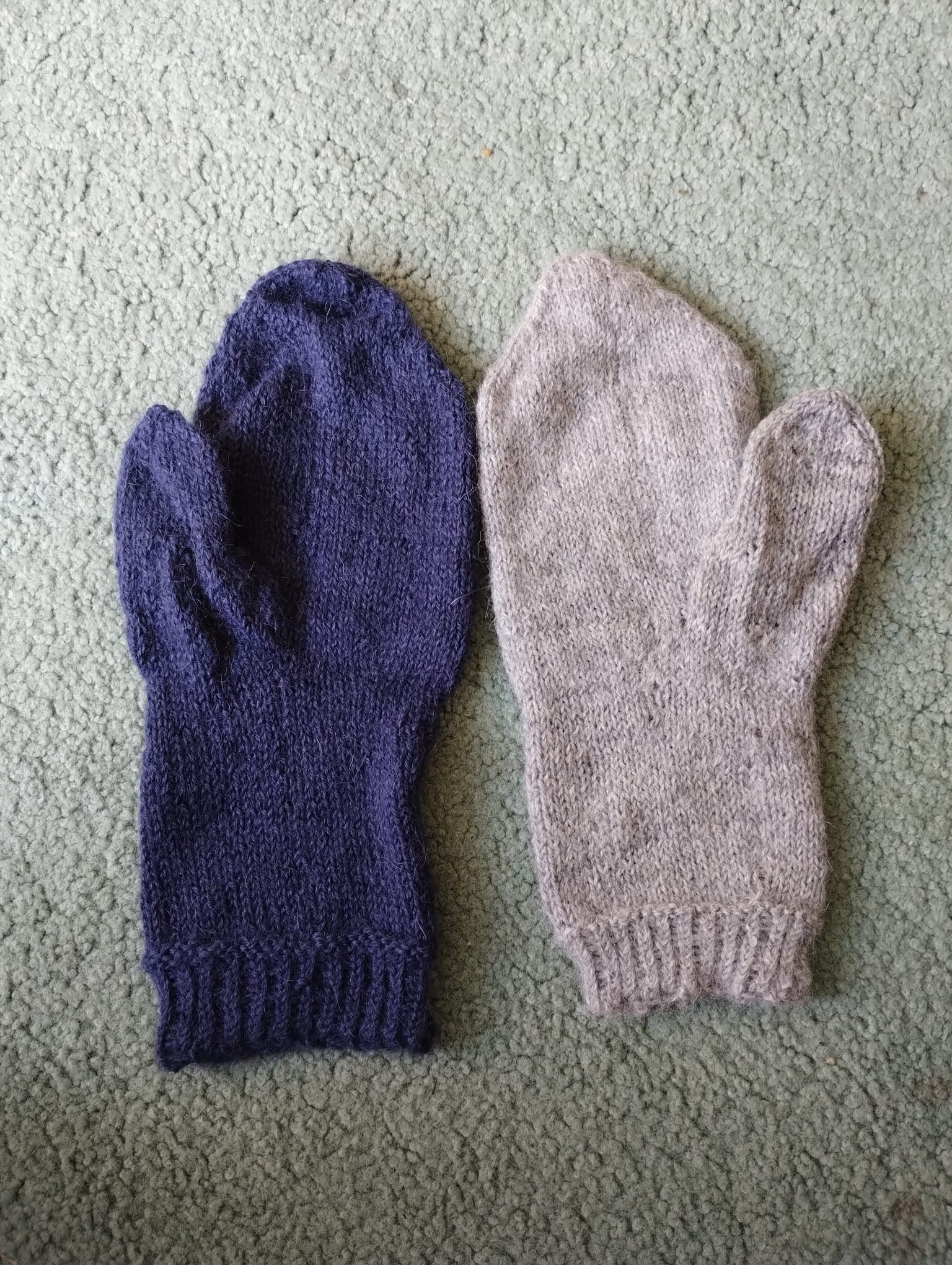 A mismatched pair of hand-knitted mittens for Mum, one navy and one oatmeal