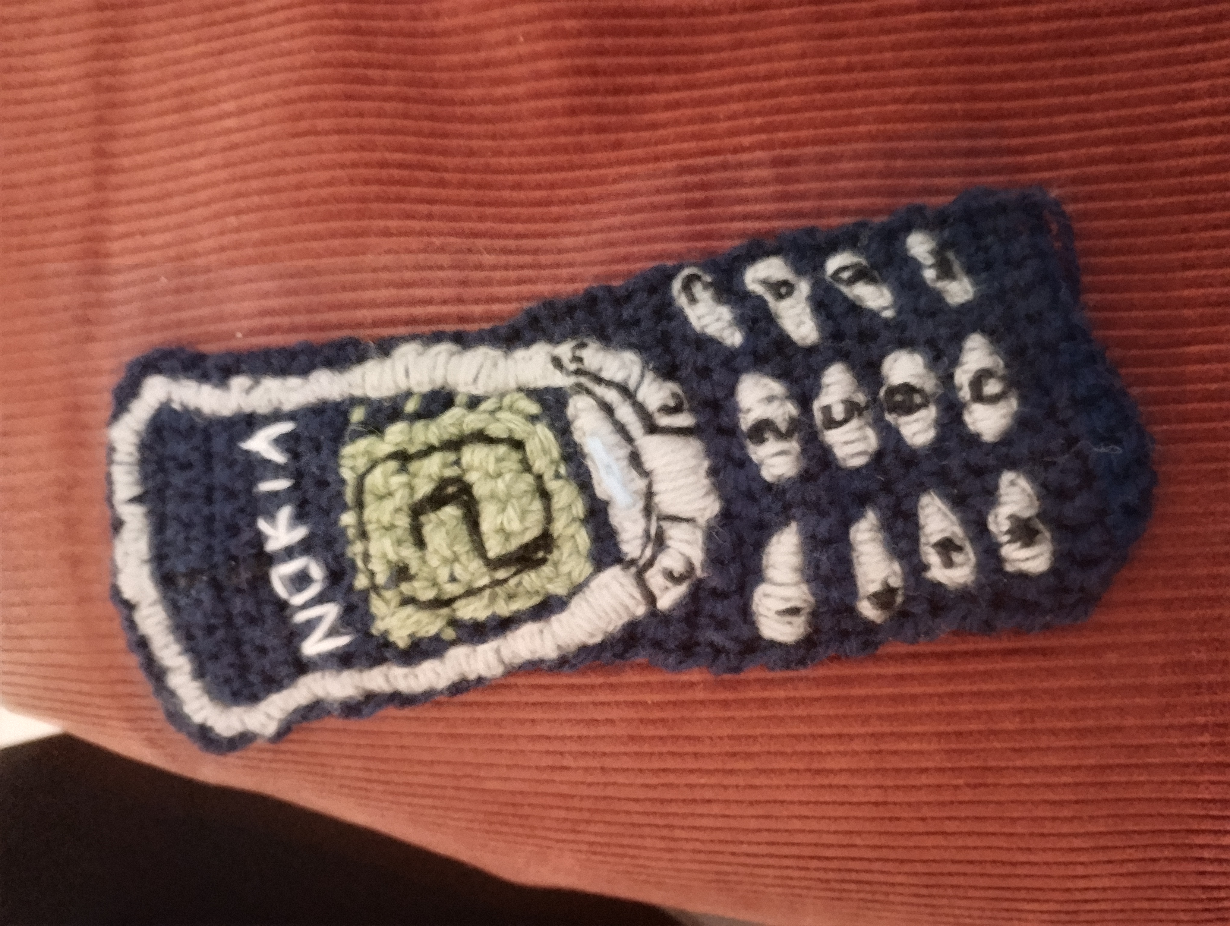 A crocheted phone case shaped like a classic Nokia handset, with the Nokia logo and a full numeric keypad worked in contrasting yarn