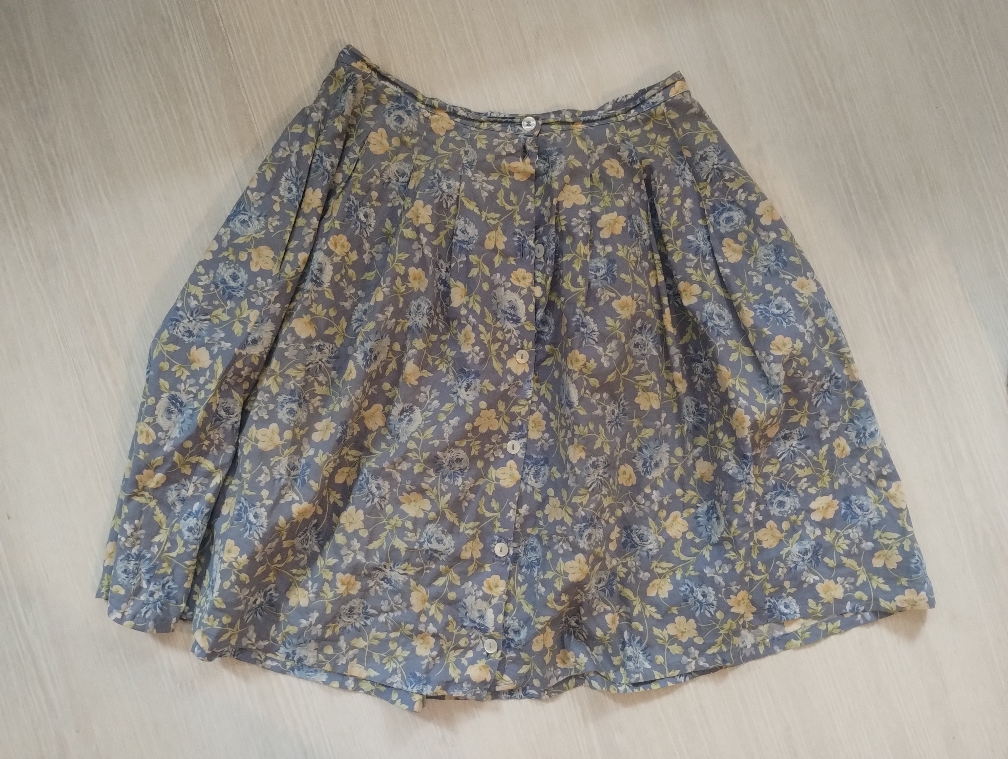 A grey floral button-front skirt laid flat, hemmed shorter than its original length