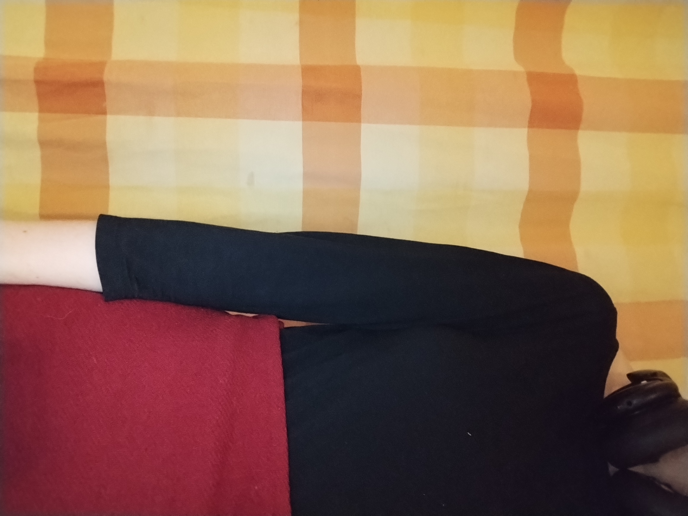 A black three-quarter-sleeve top worn over a dark red skirt